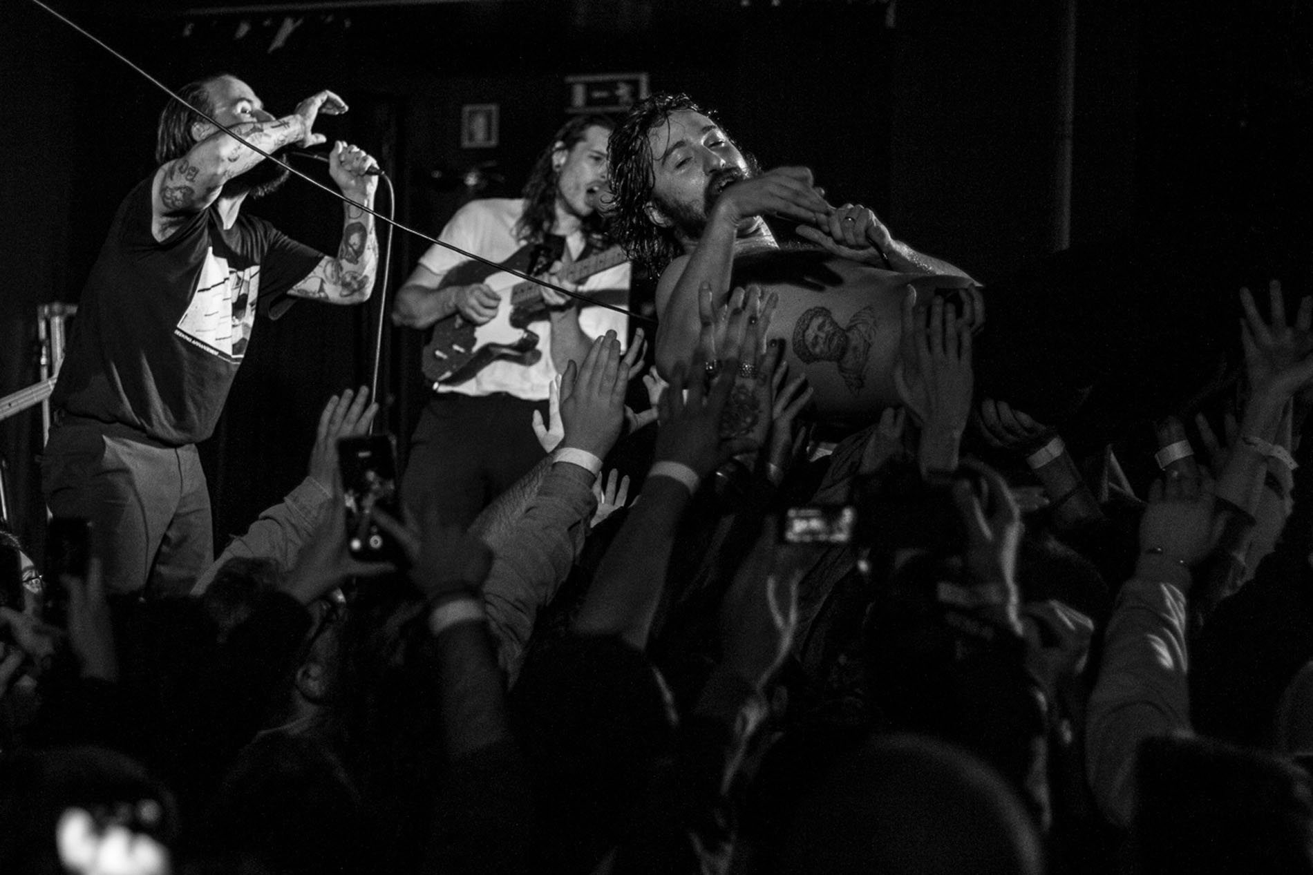Performer supported by the audience while IDLES continue playing on stage.