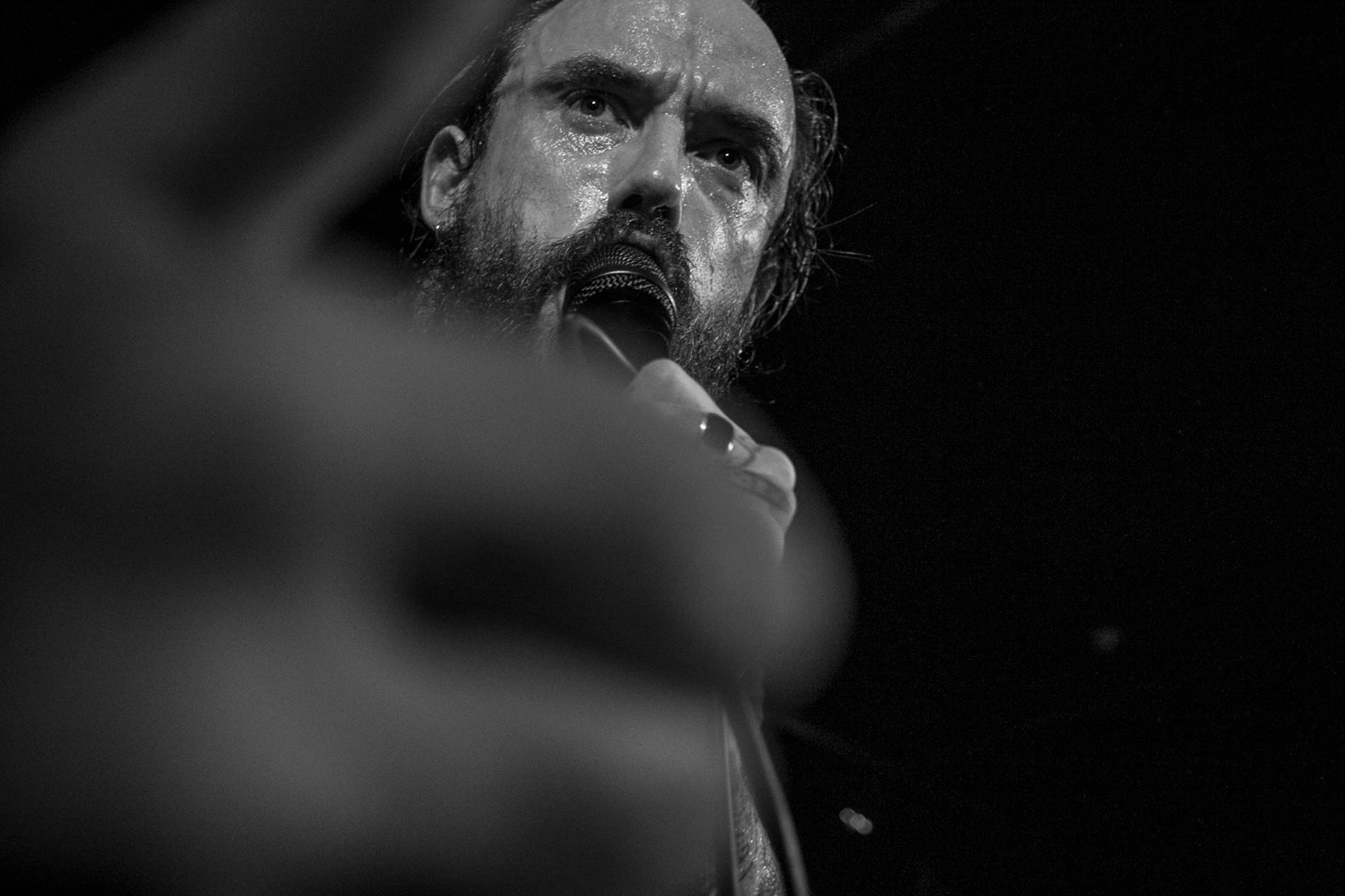 Close black-and-white photograph of the IDLES vocalist during the Hard Club performance.