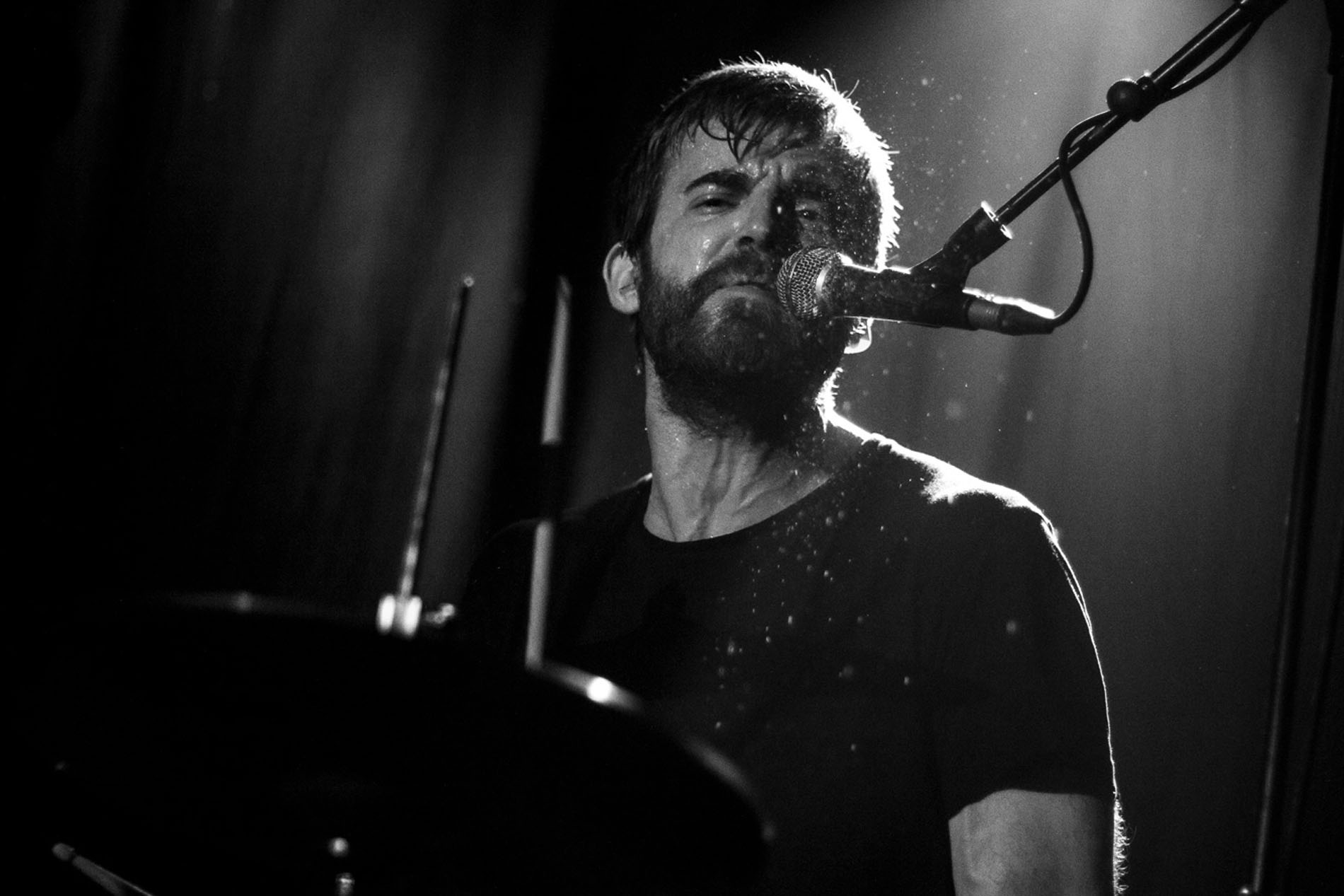 Musician from JOHN performing under stage lighting at Hard Club in Porto.